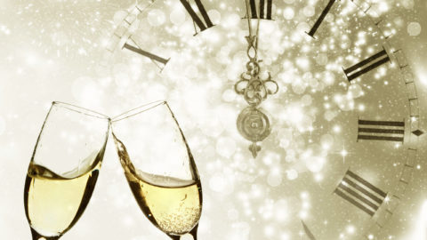 Champagne over fireworks and clock close to midnight