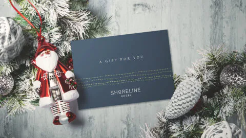 Festive Shoreline Hotel gift card with Santa ornament and winter greenery, perfect for a luxurious holiday getaway.