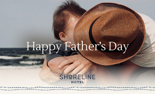 Father hugging child on sunny beach, celebrating Father's Day at Shoreline Hotel. Enjoy family-friendly coastal getaways.