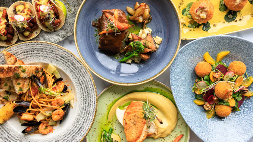 Vibrant gourmet dishes including pasta, tacos, and salads showcase our luxury hotel's diverse dining experience.