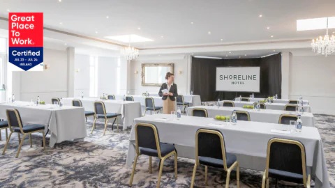 Elegant conference room at Shoreline Hotel with modern setup, natural light, and chandelier. Perfect for meetings or events.
