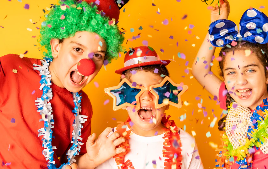 Children joyfully play in a confetti-filled room, wearing colourful wigs and hats, capturing the hotel's family-friendly fun.