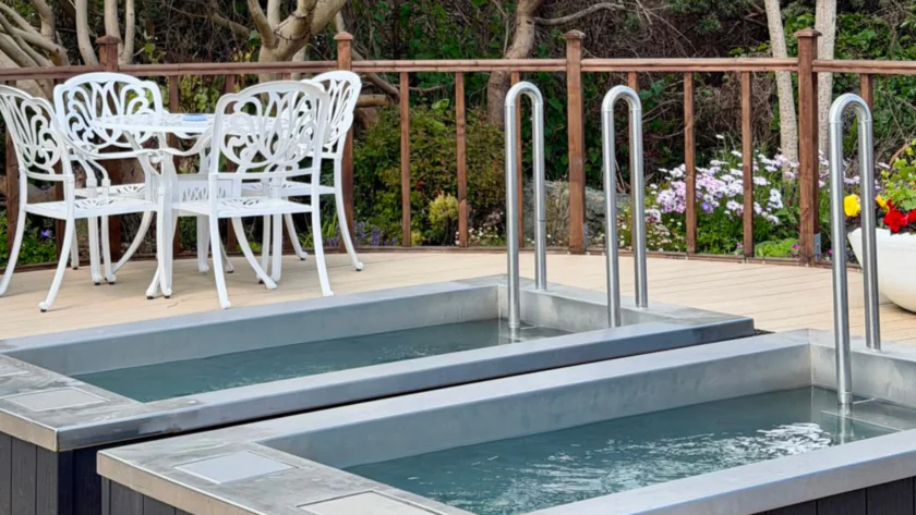 Relax by the outdoor spa pool with elegant white seating, surrounded by lush greenery and colourful flowers.